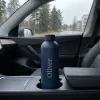 Tummansininen personoitu termospullo auton mukitelineessä sateisella matkalla
